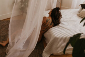 Elopement Photographer, woman lays undressed at foot of her bed